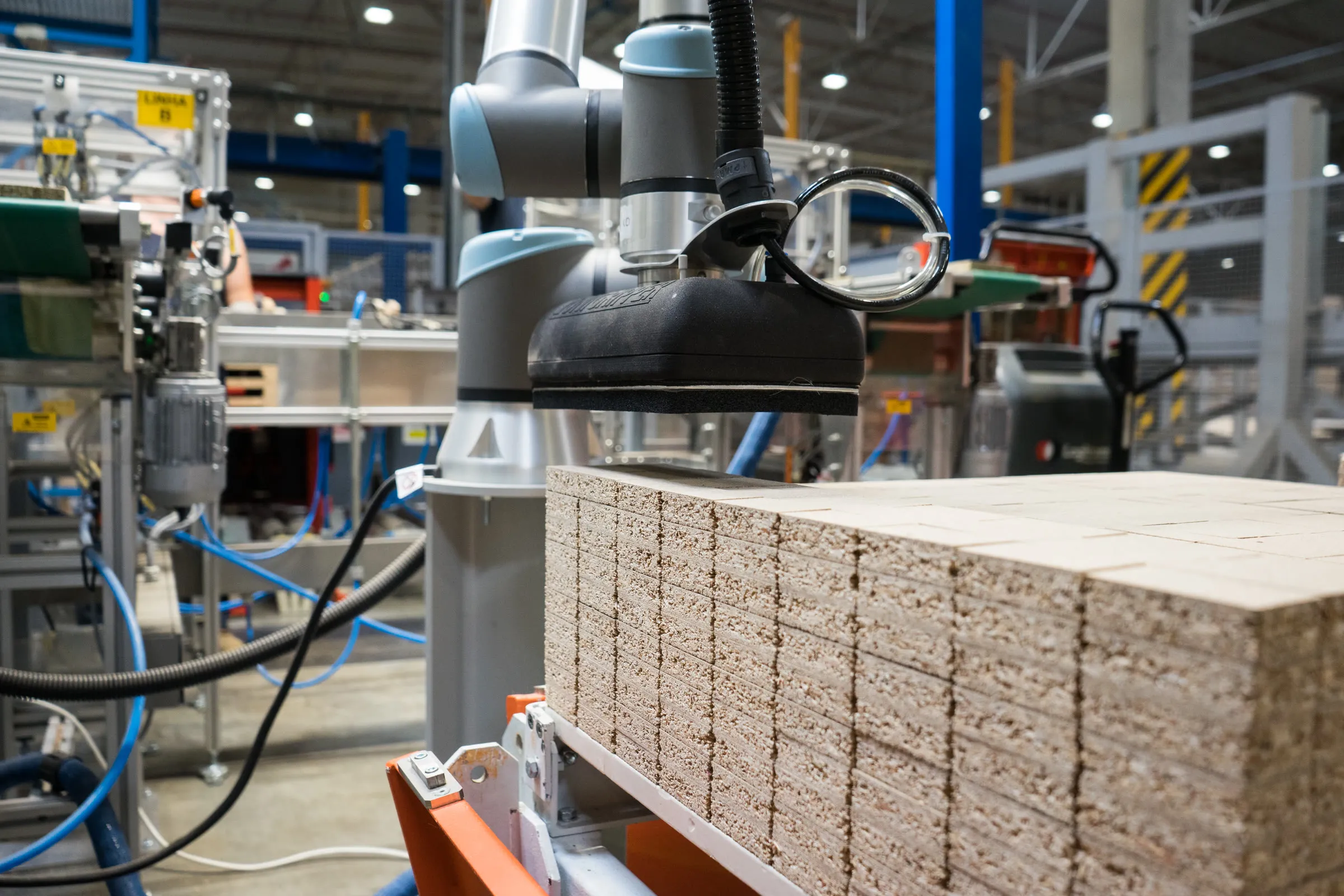 The UR10e arm over stacked panels at the pre-assembly station